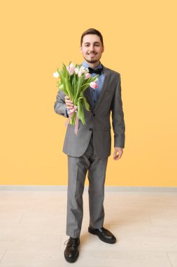 Sarı duvarın yanında güzel lalelerle dolu bir buketi olan genç adam. Uluslararası Kadınlar Günü
