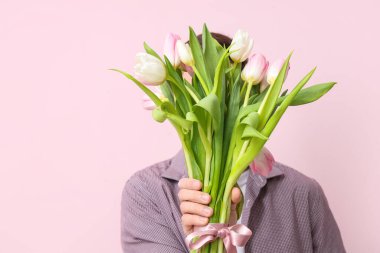 Pembe arka planda bir buket güzel lalesi olan genç bir adam. Uluslararası Kadınlar Günü