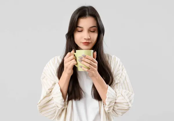 灰色の背景に紅茶のカップを持つかなり若い女性 — ストック写真