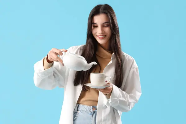 Schöne Junge Frau Gießt Tee Aus Kanne Tasse Auf Blauem — Stockfoto