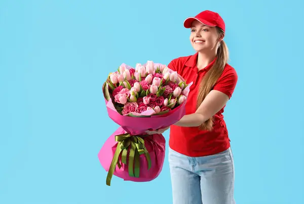 Female courier with bouquet of flowers on blue background