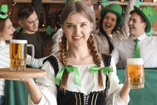 Young waitress with beer in bar on St. Patrick\'s Day