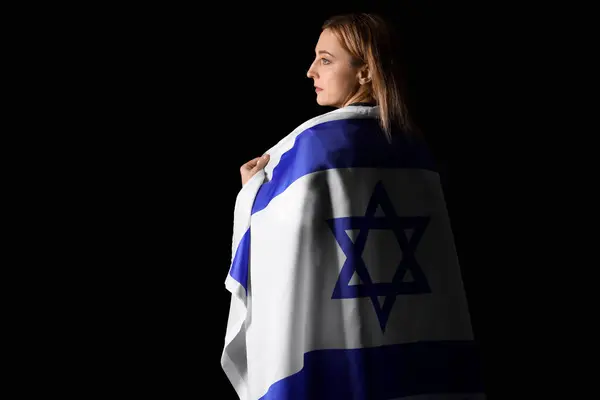 Mature woman with flag of Israel on black background, back view. International Holocaust Remembrance Day