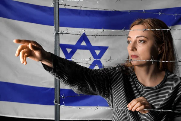 Mature woman behind barbed wire against flag of Israel. International Holocaust Remembrance Day