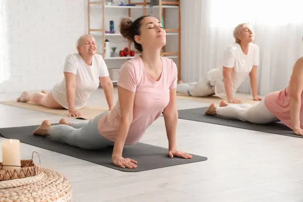 Mature woman doing yoga with group in gym