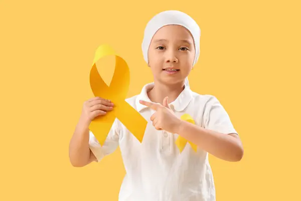 可爱的亚洲小女孩化疗后指着黄丝带的彩色背景 儿童癌症意识概念 — 图库照片