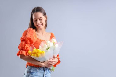 Hafif arka planda lale buketleri olan genç bir kadın. Uluslararası Kadınlar Günü