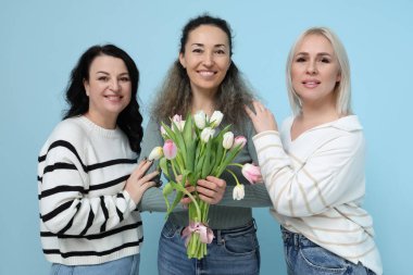 Mavi arka planda bir buket güzel lalesi olan olgun kadınlar. Uluslararası Kadınlar Günü