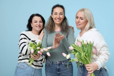 Mavi arka planda güzel lale buketleri ve parfümlü olgun kadınlar. Uluslararası Kadınlar Günü