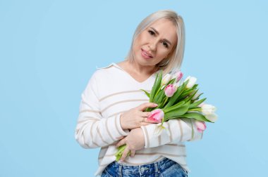 Mavi arka planda bir buket güzel lalesi olan olgun bir kadın. Uluslararası Kadınlar Günü