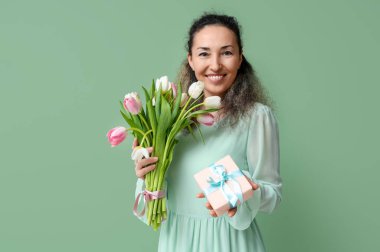 Bir buket güzel lalesi ve yeşil arka planda hediye kutusu olan olgun bir kadın. Uluslararası Kadınlar Günü