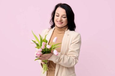 Pembe arka planda güzel lalelerle dolu buketi olan mutlu olgun bir kadın. Uluslararası Kadınlar Günü