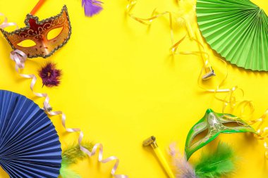 Karnaval maskelerinden yapılmış karnaval kornaları ve Mardi Gras kutlamaları için sarı arka planda dekor.
