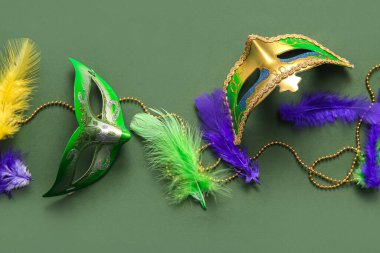 Mardi Gras için yeşil arka planda tüylü ve boncuklu karnaval maskeleri.