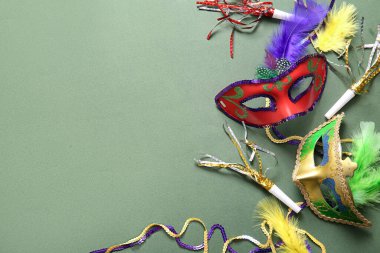 Mardi Gras için yeşil arka planda parti boynuzları ve tüyleri olan karnaval maskeleri.