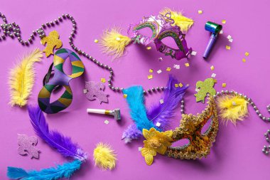 Mardi Gras için mor arka planda parti kornaları ve dekorları olan karnaval maskeleri.