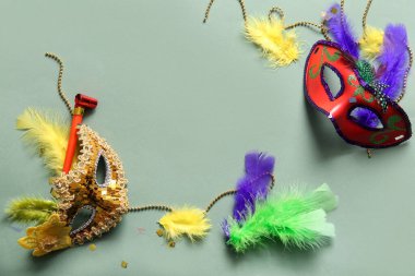 Mardi Gras için yeşil arka planda parti kornalı ve dekorlu karnaval maskeleri.