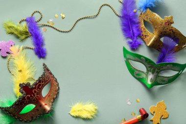 Parti kornası ve dekoru olan karnaval maskelerinden yapılmış çerçeve yeşil arka planda Mardi Gras kutlaması için