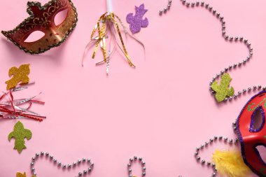 Parti kornaları ve dekorlarıyla karnaval maskelerinden yapılmış çerçeve pembe arka planda Mardi Gras kutlaması için