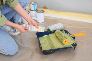 Renkli paleti olan genç bir kadın odada tamirat yapıyor, yakın plan.