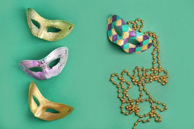 Mardi Gras kutlamaları için boncuklu parlak karnaval maskeleri yeşil arka planda.