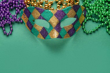 Yeşil arka planda Mardi Gras kutlamaları için boncuklu parlak karnaval maskesi
