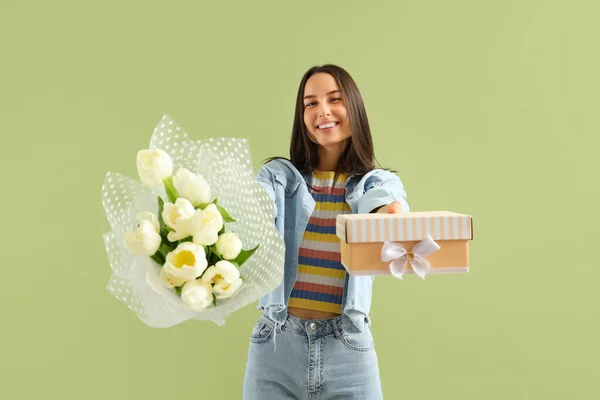 Young woman with bouquet of tulips and gift on green background. International Women's Day