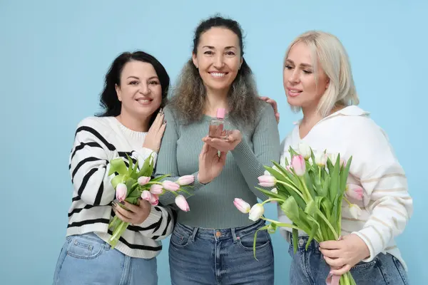 Mavi arka planda güzel lale buketleri ve parfümlü olgun kadınlar. Uluslararası Kadınlar Günü