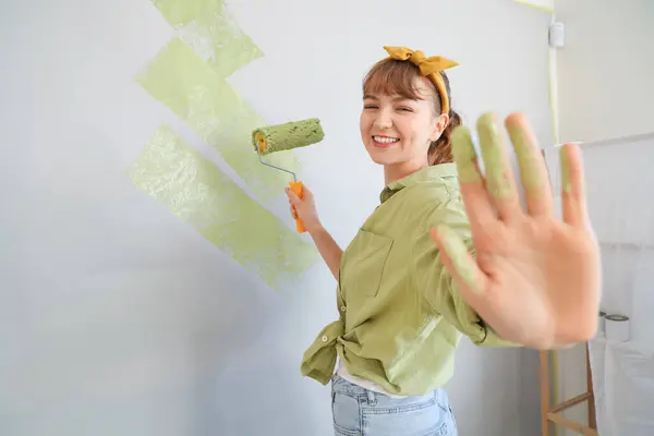 Young woman painting wall during repair in room