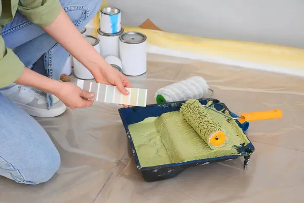 Renkli paleti olan genç bir kadın odada tamirat yapıyor, yakın plan.