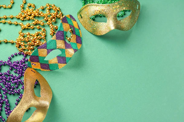 Mardi Gras kutlamaları için boncuklu parlak karnaval maskeleri yeşil arka planda.