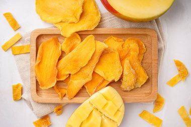 Beyaz arka planda kurutulmuş mango dilimleri olan ahşap tahta.