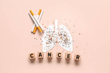 Kağıt ciğer, dağınık tütün, sigara ve bej arka planda kelime CANCER