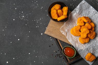 Siyah arka planda kağıt ve bir kase lezzetli nugget.