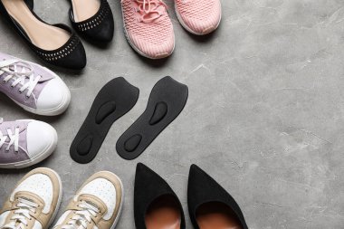 Farklı kadın ayakkabıları ve grunge arka planda siyah ortopedik tabanlar.