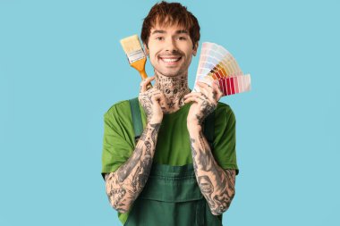 Farklı palet örnekleriyle mutlu erkek ressam ve renk arkaplanda boya fırçası