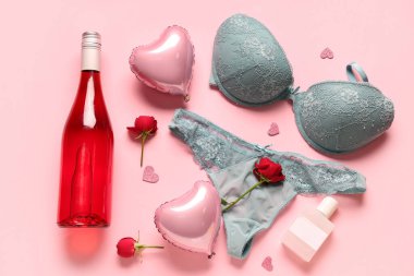 Seksi iç çamaşırlı kompozisyon, bir şişe şampanya, parfüm ve pembe arka planda balonlar. Sevgililer Günü kutlaması