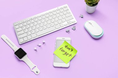 Metni olan yapışkan bir not. Leylak arkaplanındaki cihazları ve ataçları unutma.