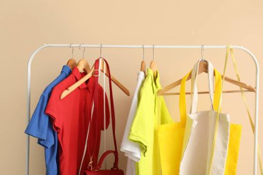 Renkli duvarın yanında farklı giysi ve çantalarla dizilin.