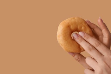 Bej arka planda donutu olan genç bir kadın, yakın plan. Seks konsepti