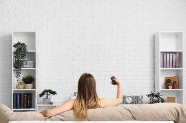 Oturma odasında televizyon izleyen genç bir kadın.