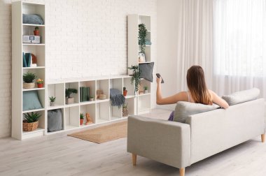 Oturma odasında televizyon izleyen genç bir kadın.