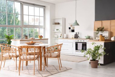 Mutfağın içinde yemek masası, tezgah ve ev bitkileri var.