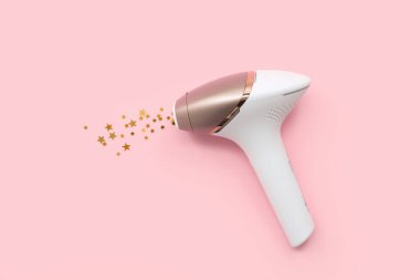 Modern fotoğraf makinesi ve pembe arka planda altın pullar.