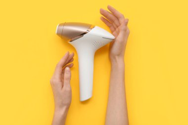 Sarı arka planda modern fotoğraf makinesi olan kadın eller, yakın plan.