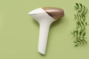 Yeşil arka planda modern fotoepilatör ve bitki yaprakları ile kompozisyon