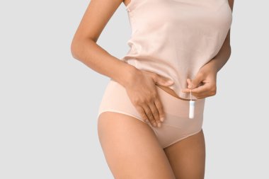 Adet donlu, mavi arka planda tamponu olan genç bir kadın.