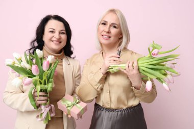 Güzel lale buketleri, ruj ve pembe arka planda hediye kutusu olan olgun kadınlar. Uluslararası Kadınlar Günü