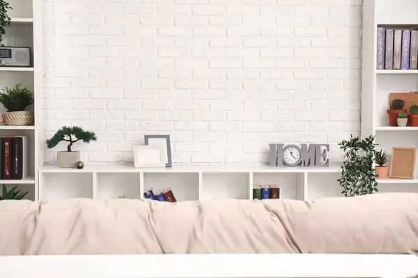 TV stand with books and plants near white brick wall in living room