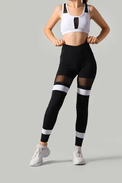Sporty young woman in leggings on light background